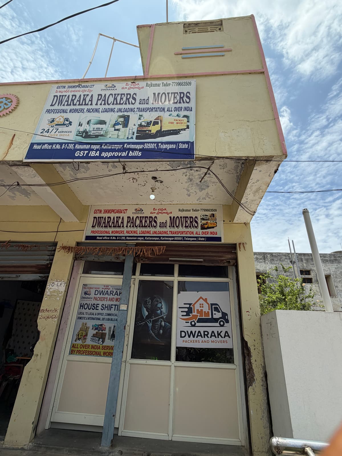 Street view of the Dwaraka Packers and Movers office building in Karimnagar with company banners on two walls
